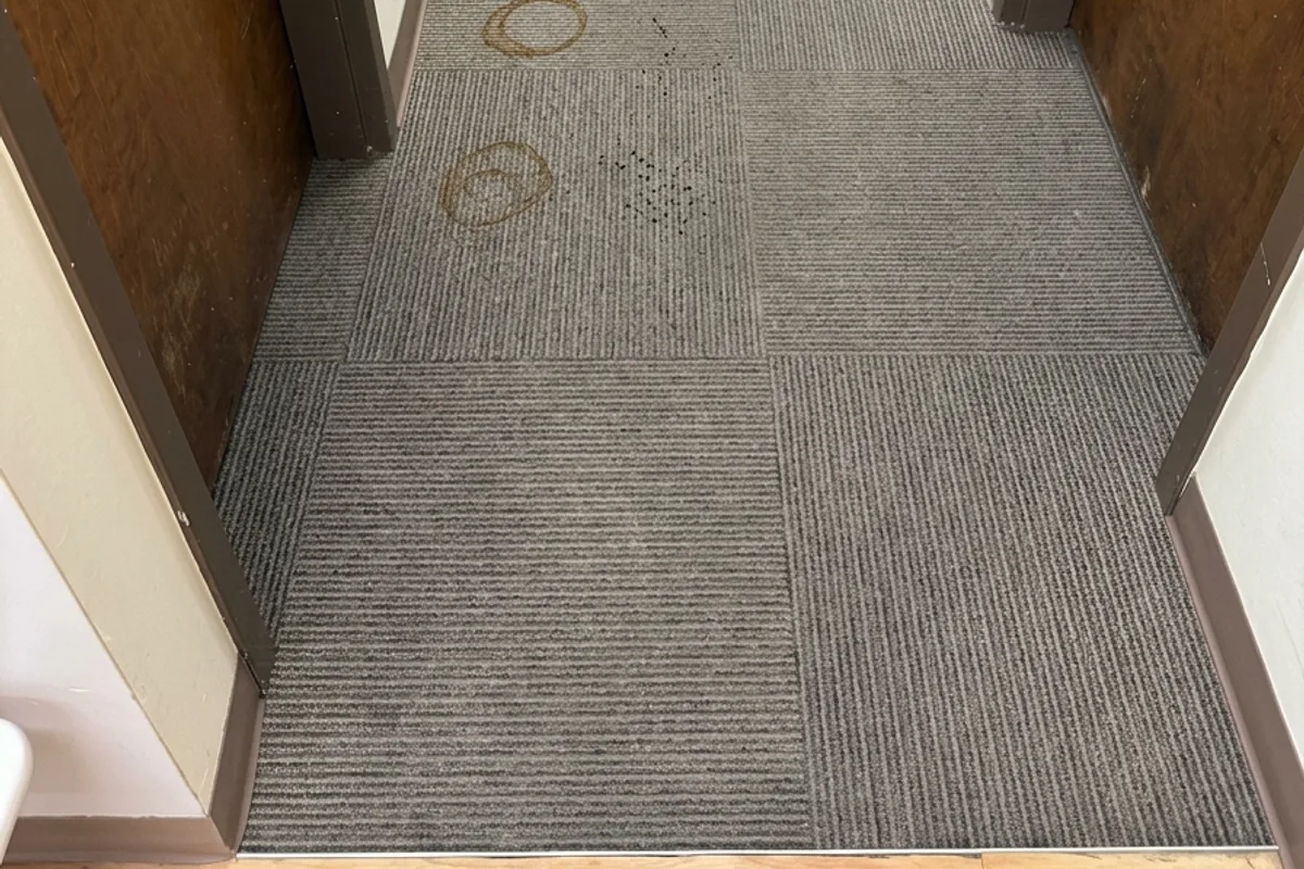 Commercial carpet tile in a Skokie office showing coffee spills and darkened traffic lanes